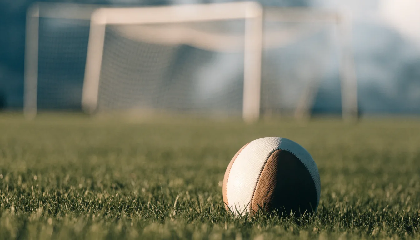 Ein Fussball auf dem Rasen aus niedriger Perspektive aufgenommen, die Torpfosten verschwimmen im Hintergrund.