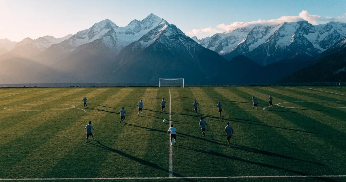 Ein Fussballplatz aus der Vogelperspektive mit sauberen Linien auf dichtem Rasen, in der Ferne verschneite Berge.