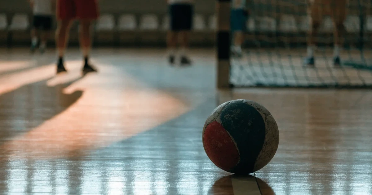 Ein Tor mit dicht gespanntem Netz steht in einer grossen Halle, davor liegt ein Handball auf der Torraumlinie.